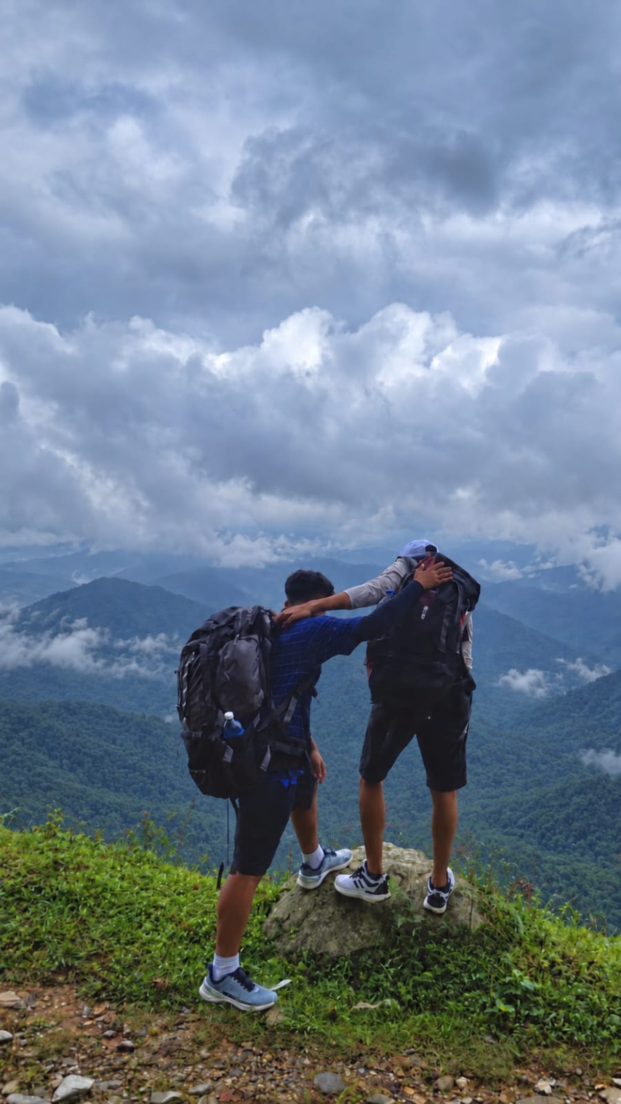 Two hikers overlooking forested mountains in Nepal